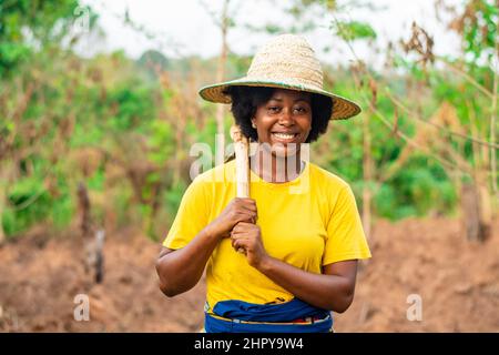 Fröhliche afrikanische Bäuerin mit Hut auf dem Feld Stockfoto