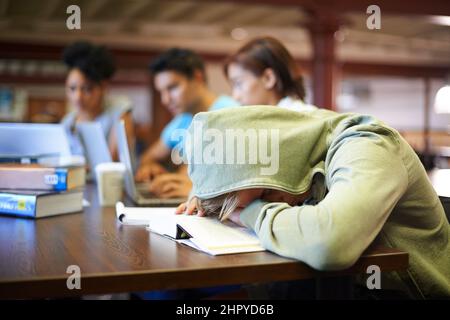 Die Belastung der bevorstehenden Untersuchungen spüren. Ein junger Student in einer Studiengruppe, der unter der Erschöpfung der Finals leidet. Stockfoto