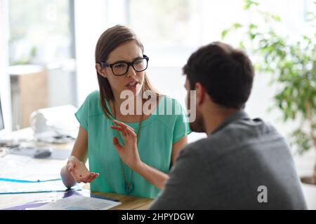 Stellen Sie sicher, dass das Bild klar ist. Aufnahme eines jungen Designers, der einem Kollegen etwas erklärt. Stockfoto