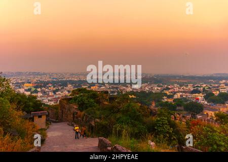 Ein Blick auf Hyderabad, Indien, vom Gipfel des Golconda Forts. Die untergehende Sonne wirft ein gelblich-oranges Leuchten über den Himmel über der Stadt der Perlen. Stockfoto