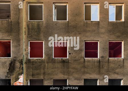 Beschädigtes gemauertes Haus mit kaputten Fenstern und beschädigter schmutziger Fassade Stockfoto