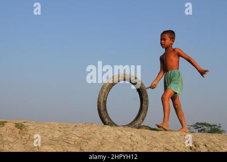 Khulna, Bangladesch - 08. Oktober 2014: Ein Kind spielt mit einem Motorradreifen im Küstengebiet von Khulna in Bangladesch. Stockfoto