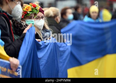 Köln, Deutschland. 24th. Februar 2022. Demonstranten stehen in einer Menschenkette mit ukrainischer Flagge. Mehrere hundert Menschen demonstrieren auf dem Neumarkt gegen den Angriff Russlands auf die Ukraine. Quelle: Federico Gambarini/dpa/Alamy Live News Stockfoto