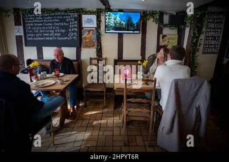 Russland erobert die Ukraine, im Fernsehen in der Weinbar Thaxted Essex, Großbritannien. 24th. Februar 2022. Während Kunden der Parrisges Wine Bar in Thaxted Essex UK ihr Mittagessen einnehmen, zeigt das Fernsehgerät Berichte auf der BBC, die die Invasion der Ukraine durch Russland heute zeigen. Kredit: BRIAN HARRIS/Alamy Live Nachrichten Stockfoto