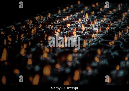 Detail von vielen roten Votivkerzen leuchten im chinesischen Tempel. Reihen von Windlicht-Kerzen im Glas mit geringer Schärfentiefe, verschwommen von Kerzen, Rot ca. Stockfoto