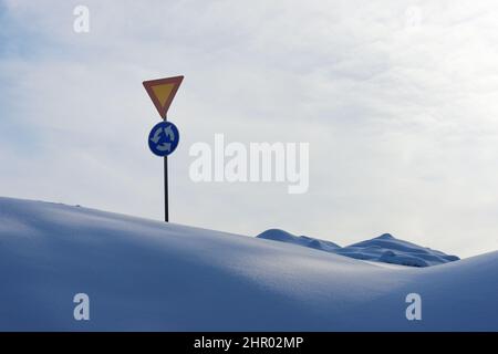 Kreisverkehr Zeichen und geben im Winter zwischen Schneeverwehungen irgendwo in Finnland Stockfoto