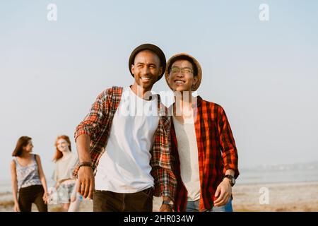 Junge multirassische Freunde, die lachen und beiseite schauen, während sie draußen gehen Stockfoto