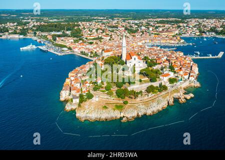 Kirche der heiligen Euphemia hoher Turm in der Stadt Rovinj, umgeben vom Meer. Gebäude mit hellen Dächern auf einer Halbinsel mit grünen Wäldern. Luftpanorama Stockfoto