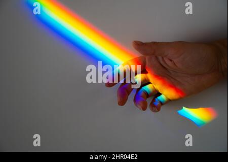 Regenbogenstrahl auf der Hand einer Frau. Stockfoto