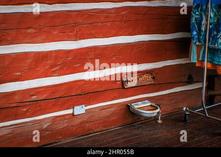Im Freien aufgepolstert Hund Wasserbrunnen auf Blockhaus Einzelhandelsgebäude mit Kleiderständer in der Nähe - Copy Space Stockfoto
