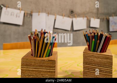 Bleistifte zum Färben in einem Holzkrug mit Kunstwerken im Hintergrund Stockfoto