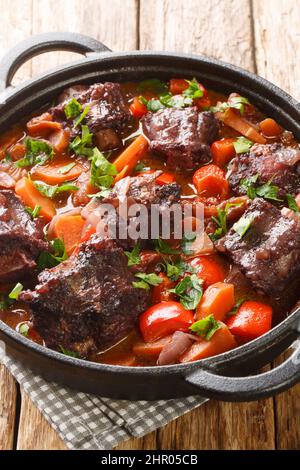 Rabo de toro oder Ochsenschwanz-Eintopf in Kochtopf aus der Nähe auf dem Teller auf dem Holztisch. Vertikal Stockfoto