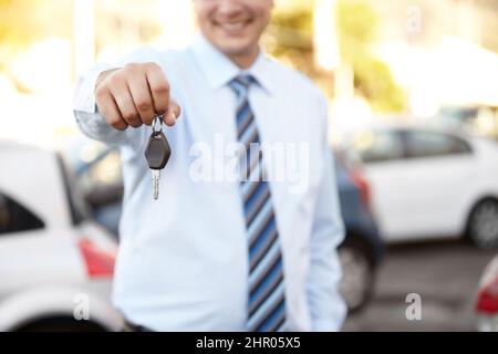 Ihr brandneues Auto wartet auf Sie. Zugeschnittenes Bild eine mans-Hand, die Ihnen einen Autoschlüssel überreicht. Stockfoto