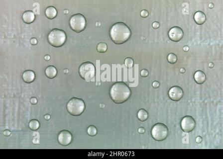 Wassertropfen auf einer silbrigen Oberfläche Stockfoto