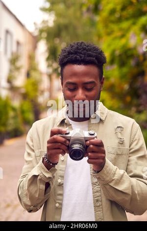 Junger Mann In Der Stadt, Der Mit Einer Digitalkamera Fotos Zur Veröffentlichung In Den Sozialen Medien Gemacht Hat Stockfoto