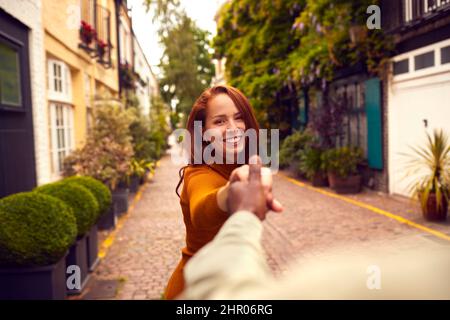 Blickwinkel Aufnahme Einer Jungen Frau, Die Den Mann Durch Die City Street Führt Stockfoto