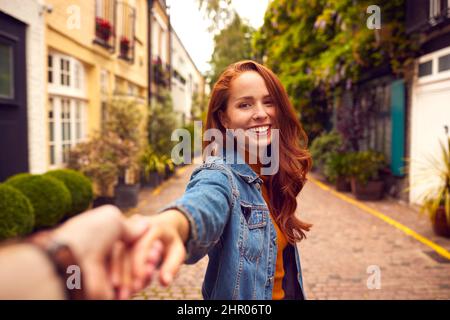 Blickwinkel Aufnahme Einer Jungen Frau, Die Den Mann Durch Die City Street Führt Stockfoto