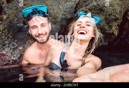 Glückliches Paar, das Selfie macht, bevor es mit wasserdichter Kamera in die Wasserhöhle kommt - Junge Menschen schnorcheln in exotischen Szenarien - Jugendstil und Reise Stockfoto