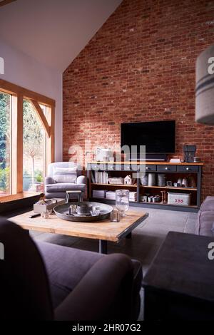 Interieur der Lounge mit TV und freiliegenden Backsteinwänden im modernen Open Plan House oder Apartment Stockfoto