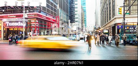 NEW YORK - 27. MÄRZ 2015: Alltag mit verschwommenem gelben Taxi, das vor Sonnenuntergang in der Nähe des Times Square in der Innenstadt von Manhattan raste Stockfoto