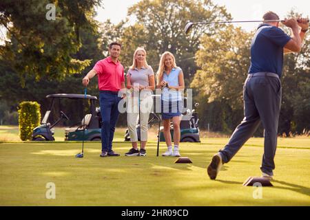 Paare Für Ältere Und Mittlere Erwachsene Stehen Am Golf Buggy Und Beobachten Den Mann Beim Hit Tee Shot Stockfoto