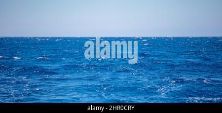 Wellenform des Ozeans Wasseroberfläche tiefblaue Farbe, kleine Wellen mit Schaum, blauer Himmel Hintergrund. Ägäisches Mittelmeer Stockfoto