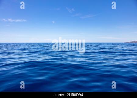 Meeresoberfläche des Ozeans tiefblau, ruhig mit Wellen, kleine Wolke auf blauem Himmel Hintergrund. Ägäisches Mittelmeer, Griechenland Stockfoto