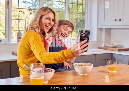 Mutter Und Sohn Zu Hause Essen Frühstücksflocken In Der Küche Und Posieren Für Selfie Auf Dem Handy Stockfoto