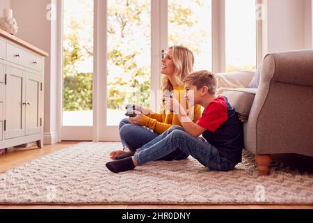 Mutter Und Sohn Sitzen Zu Hause Auf Der Lounge-Etage Und Spielen Gemeinsam Ein Videospiel Stockfoto