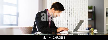 Mann sitzt in schlechter Haltung Arbeiten am Computer im Büro Stockfoto