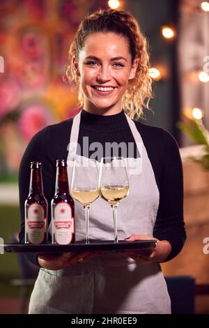 Porträt Eines Lächelnden Weiblichen Servers, Der Ein Tablett Mit Getränken In Der Cool Bar Oder Im Club Hält Stockfoto