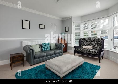 Cavendish, Suffolk - Jan 19 2019: Helles, blau-weißes Wohnzimmer mit Erkerfront und hoher Lehne und chesterfield-Sofa Stockfoto