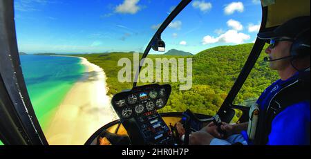 Ein Cockpit-Panorama in einem Robinson R44 Hubschrauber über eine Insel im australischen Great Barrier Reef. Stockfoto