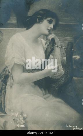 Schwarz-Weiß-Retro-Foto Anfang 20. Jahrhundert. Ein wunderschönes Mädchen, das eine antike Harfe spielt Stockfoto