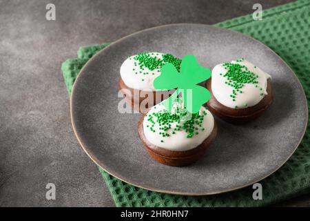 Festliche Cupcakes aus Schokolade zum Happy St. Patricks Day auf grünem Hintergrund. Nahaufnahme. Stockfoto