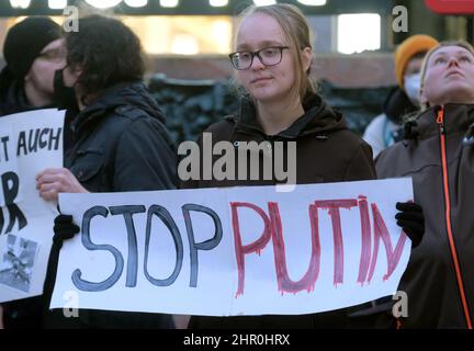 Leipzig, Deutschland. 24th. Februar 2022. Eine Frau hält bei einer Kundgebung auf dem Marktplatz ein Schild mit der Aufschrift „Stoppt Putin“. Mehrere hundert Menschen demonstrieren ihre Solidarität mit der Ukraine und gegen den Einmarsch russischer Truppen im Land. Quelle: Sebastian Willnow/dpa-Zentralbild/dpa/Alamy Live News Stockfoto