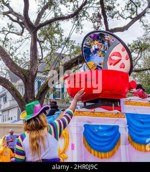 NEW ORLEANS, LA, USA - 20. FEBRUAR 2022: Frau in Mardi Gras-Kleidung mit ausgestrecktem Arm, die Perlen von Floatfahrern der Femme Fatale Parade anwirbt Stockfoto