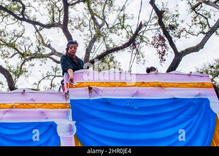 NEW ORLEANS, LA, USA - 20. FEBRUAR 2022: Frau, die Perlen von Mardi Gras wirft, schwebt während der Femme Fatale Parade auf der St. Charles Avenue Stockfoto