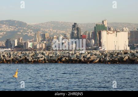 Ein Blick auf den Hafen mit den ikonischen verwüsteten Getreidesilos, Beirut, 23. Februar 2022. Die fast 50 Meter hohen Silos waren mit einer Kapazität von rund 100,000 Tonnen Getreide die größten des Landes. Sie schützten ganze Nachbarschaften vor der Explosion. Während die libanesische Regierung bis Ende des Monats Angebote für Unternehmen zum Abriss der Silos eröffnen wird, kämpfen Familien der Opfer von Sprengsätzen gegen ihren Abriss. In den sozialen Medien beschuldigen sie die Regierung, „die Zeugen getötet zu haben“, während die Verantwortlichen auf freiem Fuß sind. Den Familien der Opfer zufolge versucht die Regierung, „sie zu waschen Stockfoto