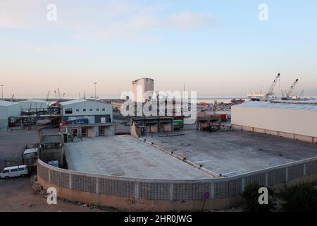 Ein Blick auf den Hafen mit den ikonischen verwüsteten Getreidesilos, Beirut, 23. Februar 2022. Die fast 50 Meter hohen Silos waren mit einer Kapazität von rund 100,000 Tonnen Getreide die größten des Landes. Sie schützten ganze Nachbarschaften vor der Explosion. Während die libanesische Regierung bis Ende des Monats Angebote für Unternehmen zum Abriss der Silos eröffnen wird, kämpfen Familien der Opfer von Sprengsätzen gegen ihren Abriss. In den sozialen Medien beschuldigen sie die Regierung, „die Zeugen getötet zu haben“, während die Verantwortlichen auf freiem Fuß sind. Den Familien der Opfer zufolge versucht die Regierung, „sie zu waschen Stockfoto