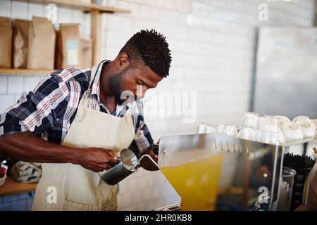 Kaffee Express. Ein kurzer Schuss eines hübschen Barista, der in einem Café eine Espressomaschine benutzt. Stockfoto