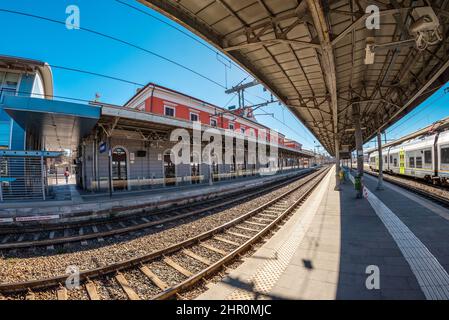 Fossano, Italien - 22. Februar 2022: Fossano Bahnhof mit Zügen am Bahnsteig, Weitwinkelansicht, regionaler Schienenverkehr im Piemont Stockfoto