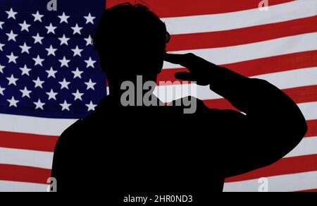 Respekt für sein Land. Silhouette eines Soldaten, der gegen eine amerikanische Flagge grüsst. Stockfoto