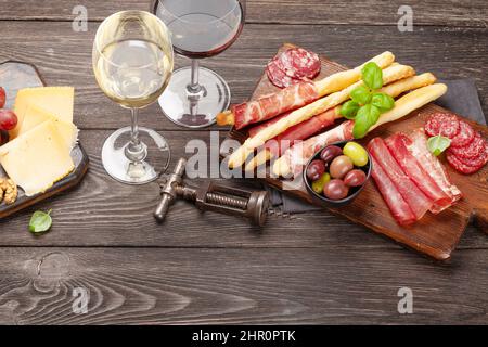 Käse, Fleisch, Trauben und Oliven Antipasto. Vorspeisenauswahl und Gläser mit Rot- und Weißwein Stockfoto