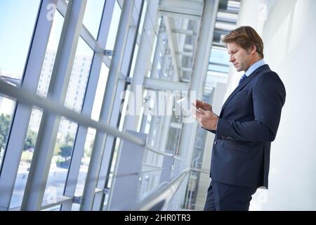 Business-Apps, die die Verwaltung erleichtern. Aufnahme eines reifen Geschäftsmannes, der mit einem digitalen Tablet in einem Büroflur steht. Stockfoto