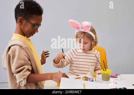 Minimal Porträt von zwei Kindern Zeichnung an Kunst und Handwerk Tisch, während genießen Osterparty für Kinder Stockfoto