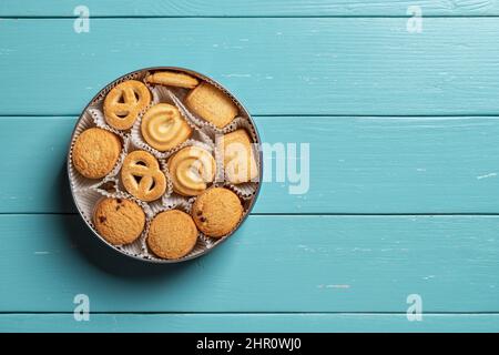 Süße dänische Butterkekse in offener Dose auf einer türkisfarbenen Holzplatte. Verschiedene knusprige Shortbread-Kekse zum Frühstück. Gebackenes Gebäck. Süßes Essen Stockfoto