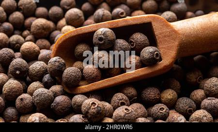 Holzlöffel voll mit pice jamaica Pfeffer Textur Nahaufnahme. Getrocknete Beeren des Pimenta-Dioica-Baumes. Bio-Gewürze, Gewürze und Gewürze. Stockfoto