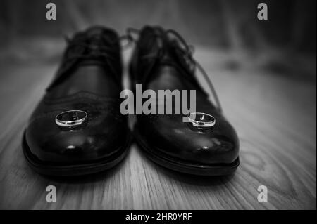 Lederschuhe für Herren, ein Paar goldene Eheringe in einer Holzkiste. Accessoires des Bräutigams Stockfoto