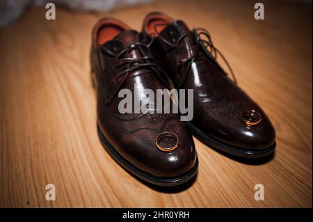 Lederschuhe für Herren, ein Paar goldene Eheringe in einer Holzkiste. Accessoires des Bräutigams Stockfoto